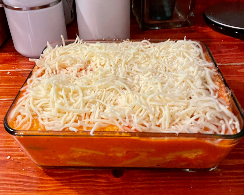 All the pasta and sauce in the pan with shredded mozzarella cheese on top before baking